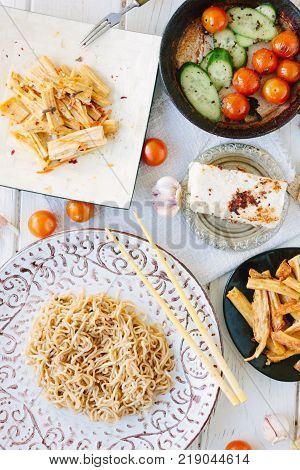 Top view of asian table with chinese noodles, roasted paneer or tofu and vegetables