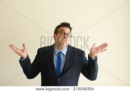 Mendacious businessman in eyeglasses expressing confusion cannot take decision. Concerned middle-aged male executive in suit shrugging arms and looking up. Misunderstanding concept