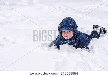 A Little Child Looks Out Of The Snow Or Pieces Of Ice. A Child Plays With Snow