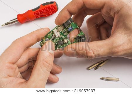 board in hands on a white background with a red screwdriver and interchangeable tips with a screwdriver