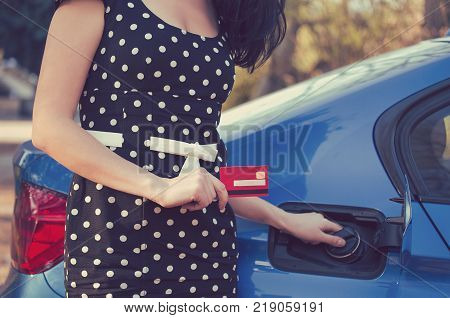 Closeup of a woman with credit card opening fuel tank of her new car