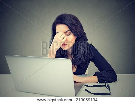 Too much work. Tired sleepy woman sitting at desk in front of laptop isolated on gray wall background. Busy schedule in college workplace sleep deprivation concept