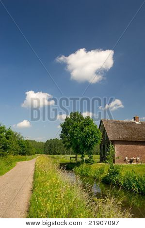 Paisagem holandesa com a vala do dique e casa no verão