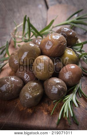 Cured, pickled or brined olive fruit on wooden table