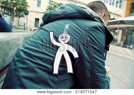 young man in the street with a paper man in his back as a prank for the dia de los inocentes, the innocents day, a feast held in spain, hispanic america and philippines equivalent to april fools day