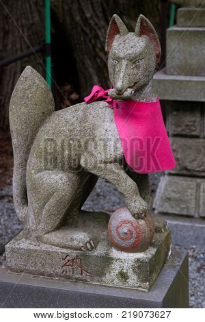 Fujiyoshida city - Japan, June 13, 2017; Votive Kitsune, fox figurine, animal guardian in front of an Inari Shrine