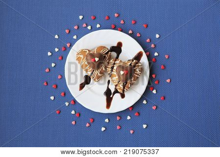 Cookies in the shape of heart on a small white plate on a blue background