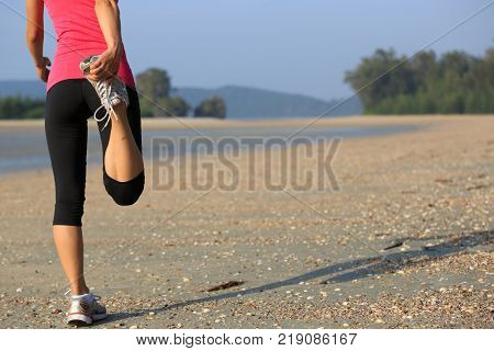 Young fitness woman warming up on sandy beach