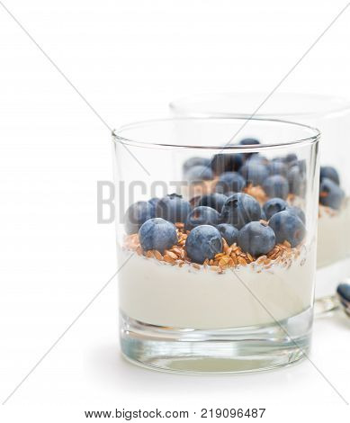 Fresh yogurt in a glass with whole flax and blueberries on white