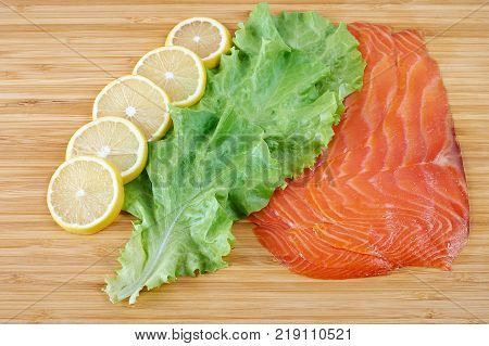 Smoked Fillet salmon with lemon and salad on a board
