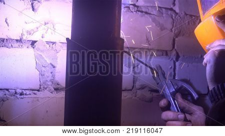 The process of manufacturing a decorative metal product. Metal sparks fly apart from the detail. Welding of metal in the process of creating decorative metal products worker supports orange mask hand.