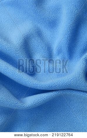 The blanket of furry blue fleece fabric. A background of light blue soft plush fleece material with a lot of relief folds