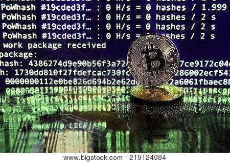 The digital process of cryptocurrency mining by using the GPUs. Bitcoins and video card on a working display and mining screen