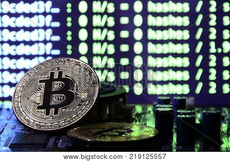 The digital process of cryptocurrency mining by using the GPUs. Bitcoins and video card on a working display and mining screen