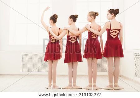 Young girls dancing ballet in studio. Choreographed dance by a group of graceful pretty young ballerinas practicing during class before performance. Classical dance school