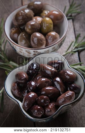 Cured, pickled or brined olive fruit on wooden table