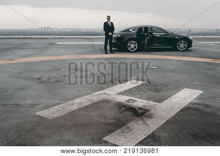 bodyguard standing close to businessman car on helipad