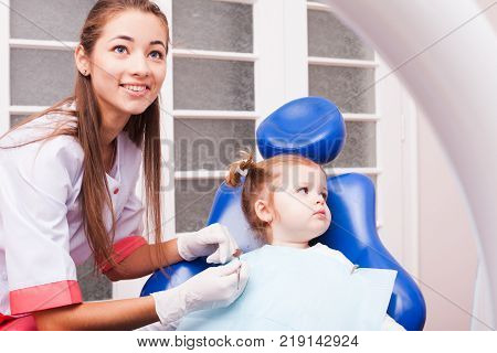 Two years old girl is on the first visit in the dental office. Young attractive dentist woman