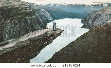 Couple Man and Woman on Trolltunga cliff raised hands mountains Love and Travel emotions Lifestyle concept. Young family traveling together active adventure vacations in Norway
