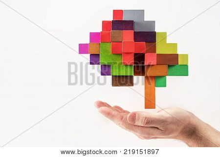 Human hand holding abstract brain. Human brain is made of multi-colored wooden blocks.