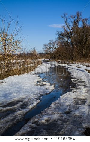 Beautiful spring landscape. Country road near the forest and fields in a sunny spring day.Snowbreak.