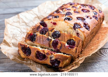 Pieces of homemade cake with cherries on a wooden background