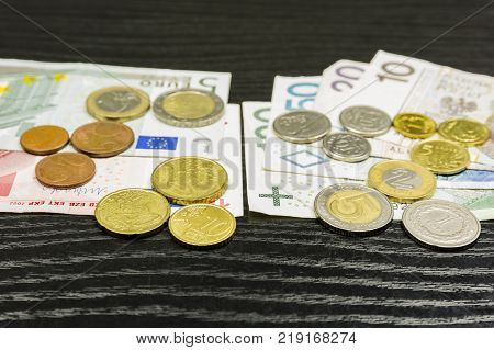 Polish currency and the euro zone on a wooden table. As a member of the European Union Poland will abandon its own and adopt the currency of the euro area.