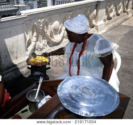 SALVADOR BRAZIL - January 2017: Brazilian woman assembles a plate of traditional acaraje fritters from a stall on the street