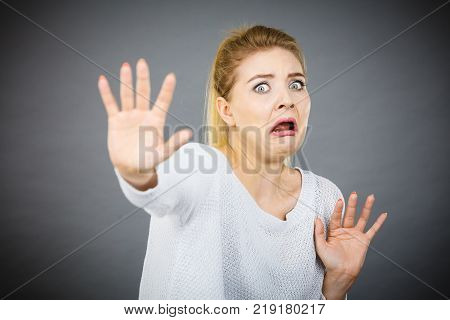 Scared woman gesturing stop gesture with hands seeing something unpleasant or scary.