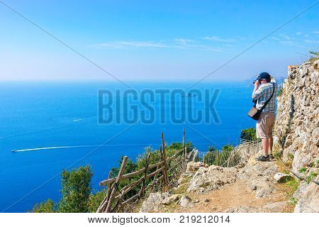 Man taking photos of beautiful scenery at Path of Gods at Tyrrhenian sea Amalfi coast Italy