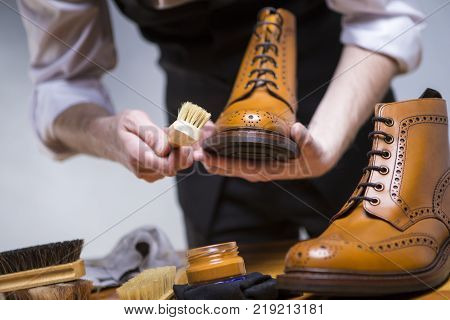 Footwear Ideas and Concepts. Extreme Close Up of Mans Hands Cleaning Luxury Calf Leather Brogues with Special Accessories Shoe Wax and Tools. Horizontal Image Composition