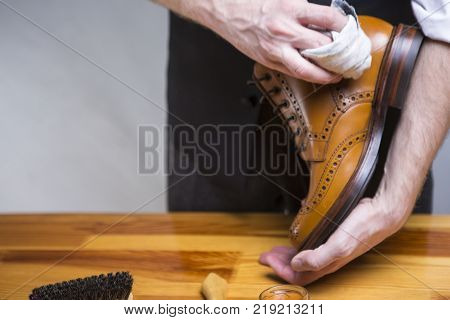 Footwear Ideas and Concepts. Extreme Close Up of Mans Hands Cleaning Luxury Calf Leather Brogues with Special Cloth. Horizontal Image