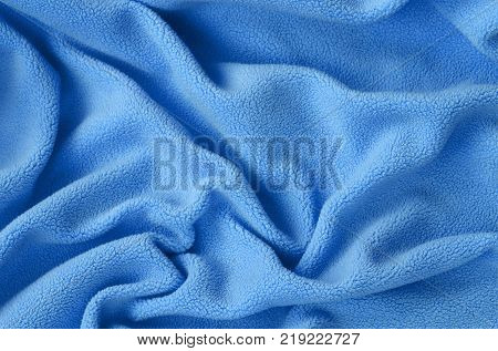 The blanket of furry blue fleece fabric. A background of light blue soft plush fleece material with a lot of relief folds