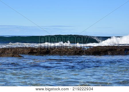 A wave crashing at the beach with rocks