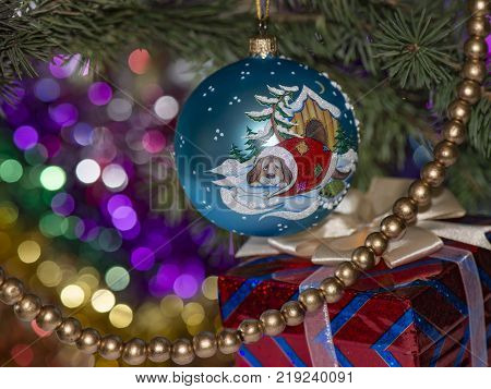 Christmas ball with the dog kennels on the spruce branch with beads and gift box with a cream bow.