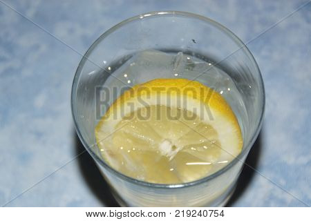 A glass with a slice of lemon and some ice cubes.  The lemon (or yellow lemon) is a citrus fruit, a fruit of the lemon tree, the juice of which has a pH of 2,5. The lemon tree (Citrus silt) is a shrub of 5 10 meters away from high, evergreen, of the famil