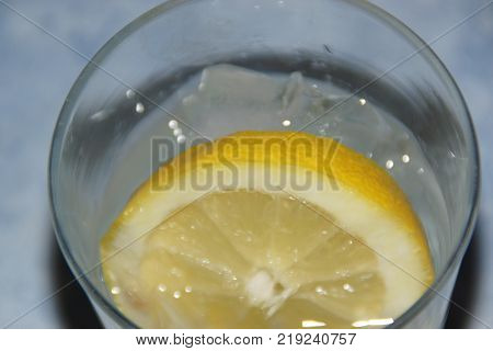 A glass with a slice of lemon and some ice cubes.  The lemon (or yellow lemon) is a citrus fruit, a fruit of the lemon tree, the juice of which has a pH of 2,5. The lemon tree (Citrus silt) is a shrub of 5 10 meters away from high, evergreen, of the famil