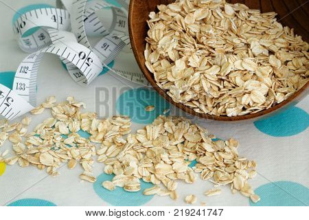 Rolled oats in a wooden bowl with tape measure