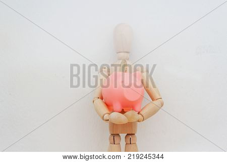 Dummy / ball-jointed doll holding pink piggy bank on isolated white background