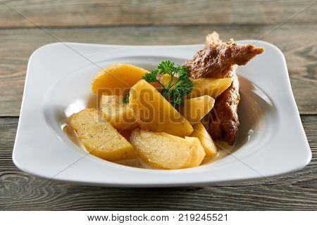 Little white restaurant plate served with goldy fried potato slices, thin sausage and decorated with parsley leaves. Looks very delicious and nourisihing.