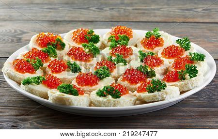 Canapees with butter, red caviar and parsley, served for restaurant catering or buffet. Good for light alcohol drinksand other meals.