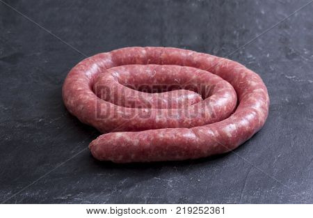 Rolled uncooked botifarra or Catalan sausage. Isolated over black slate