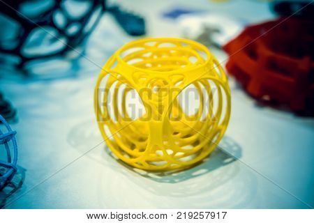 Abstract object of a yellow color printed on a 3d printer on a white table. Fused deposition modeling, FDM. Progressive modern additive technology. Concept of 4.0 industrial revolution
