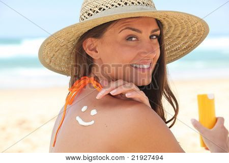 Žena použití suncream na pláži