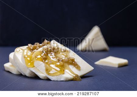 Suluguni cheese walnut and honey on black slate platter closeup