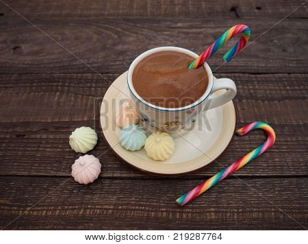 Freshly brewed cocoa and colorful biseza with candy on an old wooden table