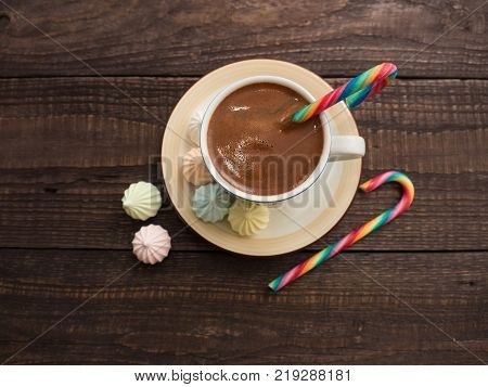 Freshly brewed cocoa and colorful biseza with candy on an old wooden table