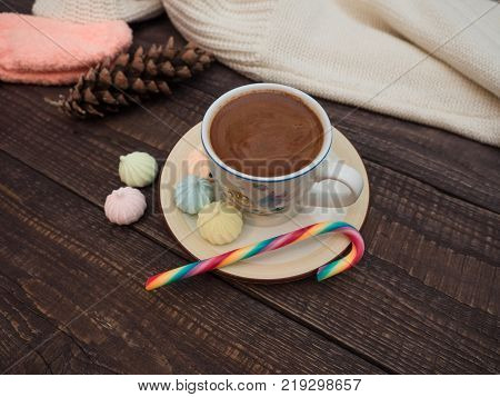 Freshly brewed cocoa and colorful biseza with candy on an old wooden table