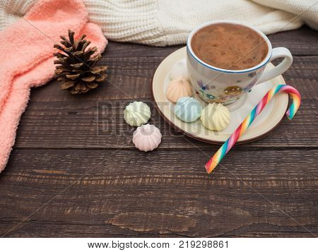 Freshly brewed cocoa and colorful biseza with candy on an old wooden table
