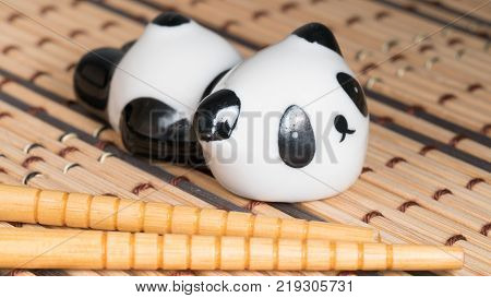 Wooden chopsticks on a food stand panda doll on a light bamboo mat